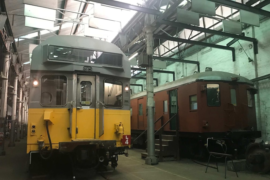 Two disused trains in a warehouse.