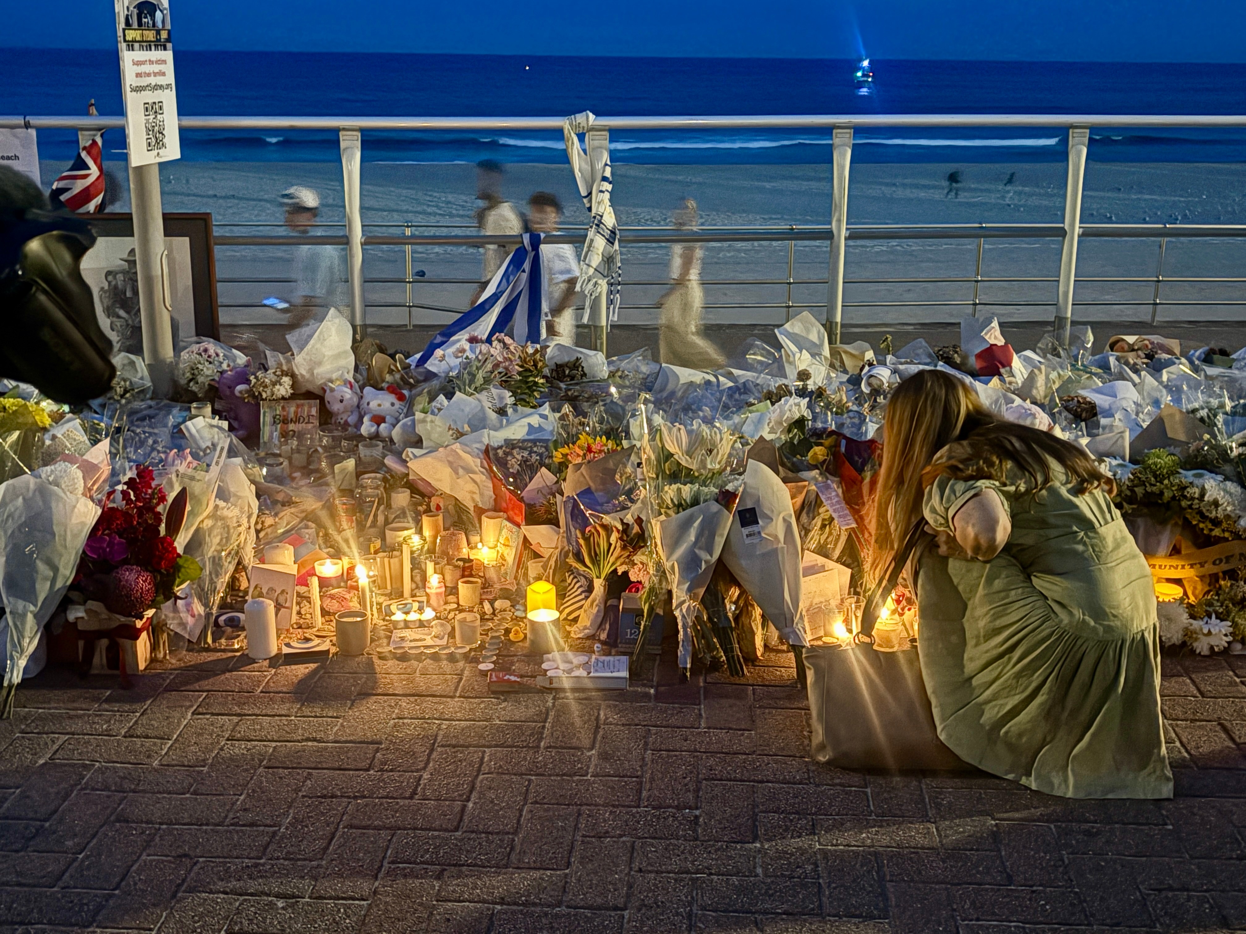 Os enlutados acendem velas e deixam flores ao longo do calçadão de Bondi Beach.