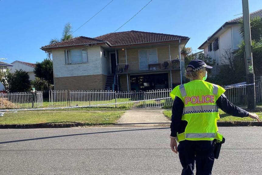 A female police officer gestures as she approaches a house.