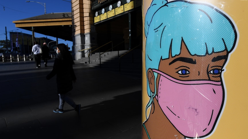 A close up of street art showing a woman with blue hair wearing a pink mask, with commuters walking in background