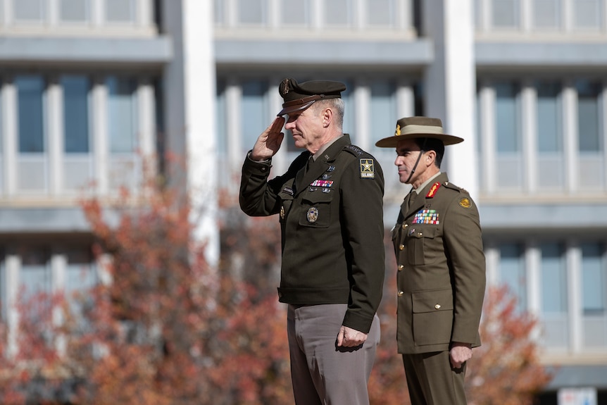 James McConville and Simon Stuart stand in military dress. Both are facing to the left, with the US General saluting. 