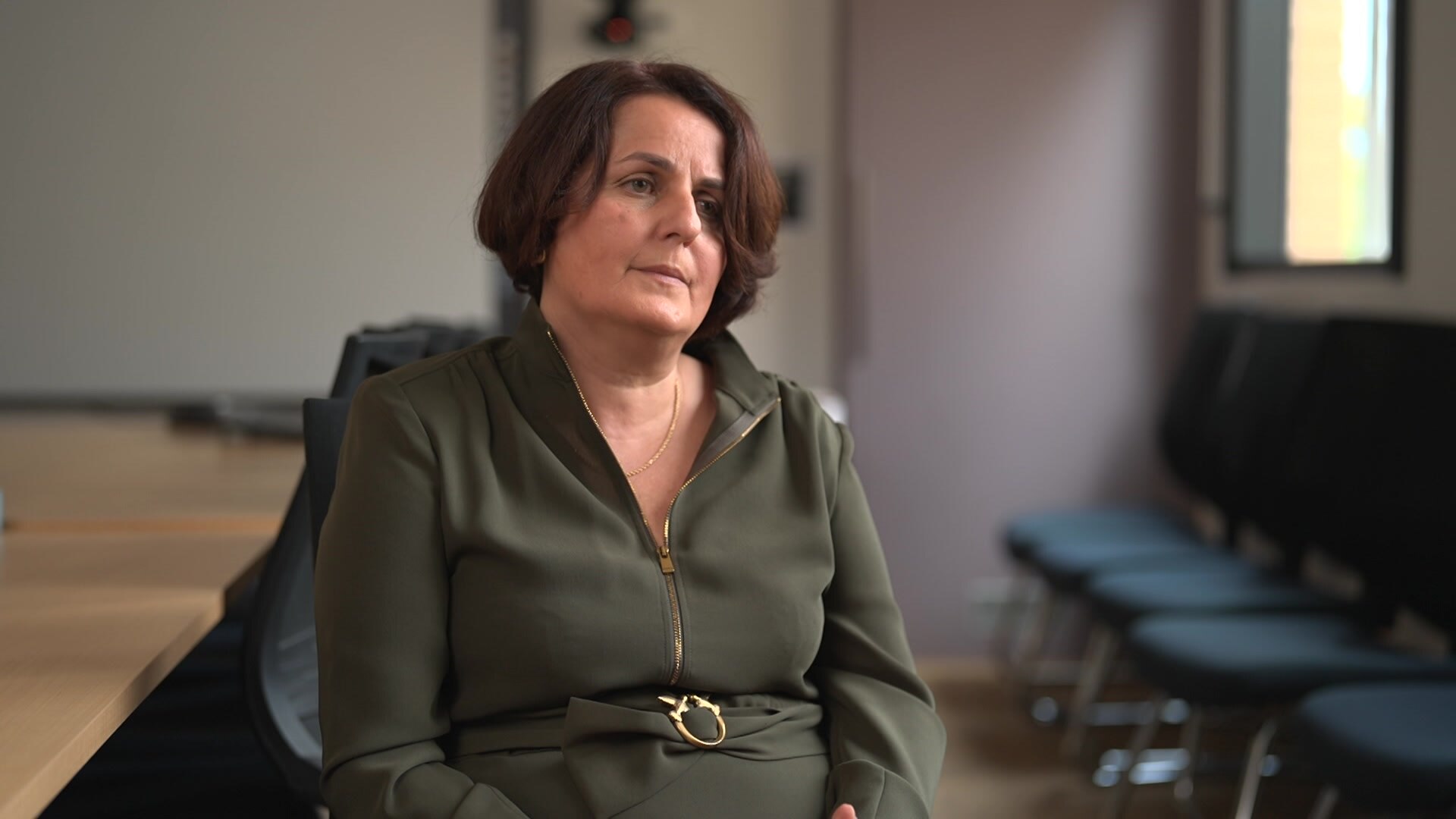 A woman with dark curly hair has a slight smile for the camera. 