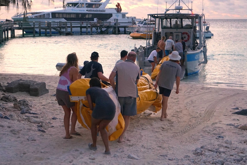 Scientists loading large mesh nets onto a boat at the Heron Island Research Station.