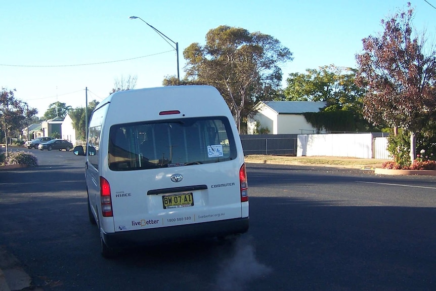 The back of a mini van driving down a street in a country town