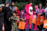 Children in Halloween costumes clutching orange bags