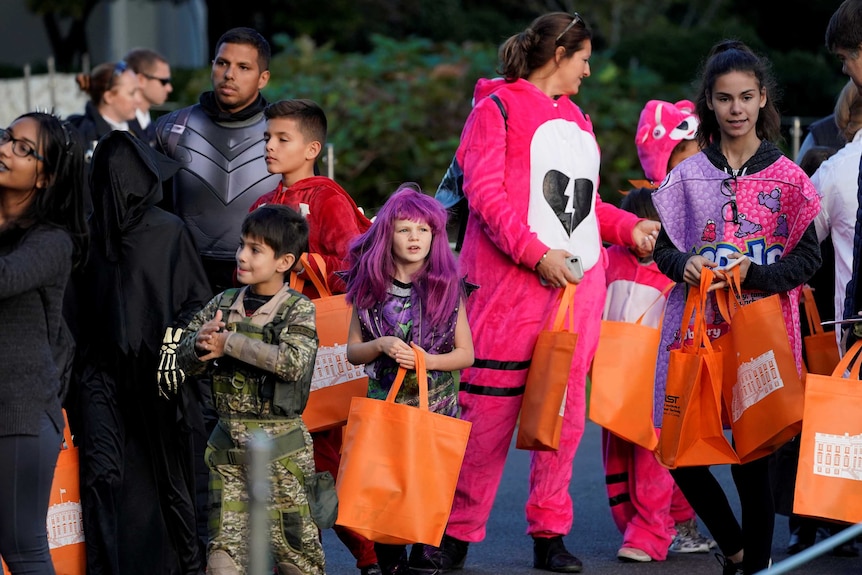 Children in Halloween costumes clutching orange bags