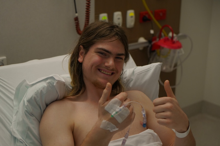 Man giving thumbs up from a hospital bed