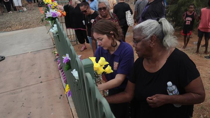 Two women put flowers on a fence as part of the vigil.