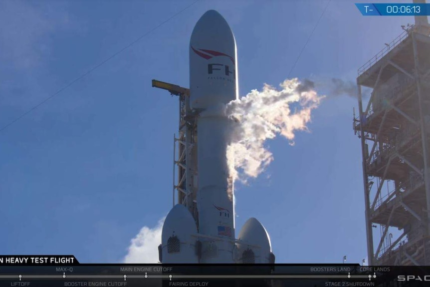 A rocket sits docked with puffs of steam or smoke visible.