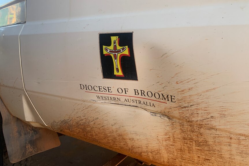 A mud-spattered logo saying Diocese of Broome on a dented car door.