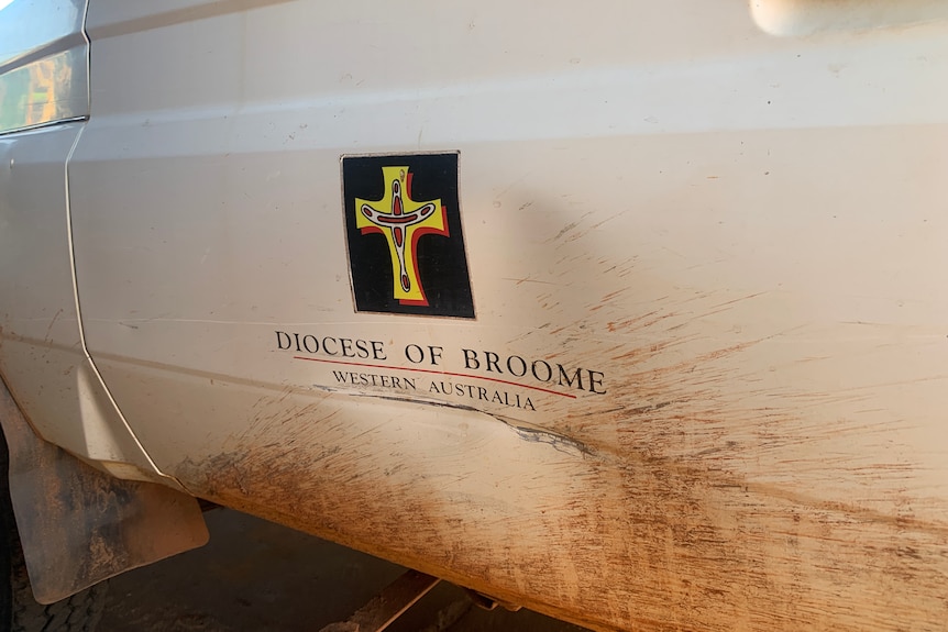 A mud-spattered car door with logo saying Diocese of Broome