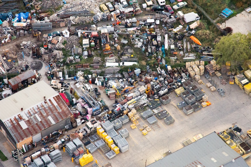 An industrial area with strewn car bodies and neatly organised storage yard.