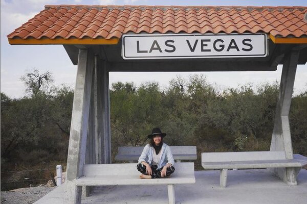 Yasmin Bright sits at a bus stop with the words Las Vegas written above it. 