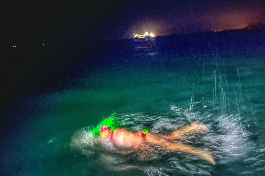 A blurry image of a man swimming at night