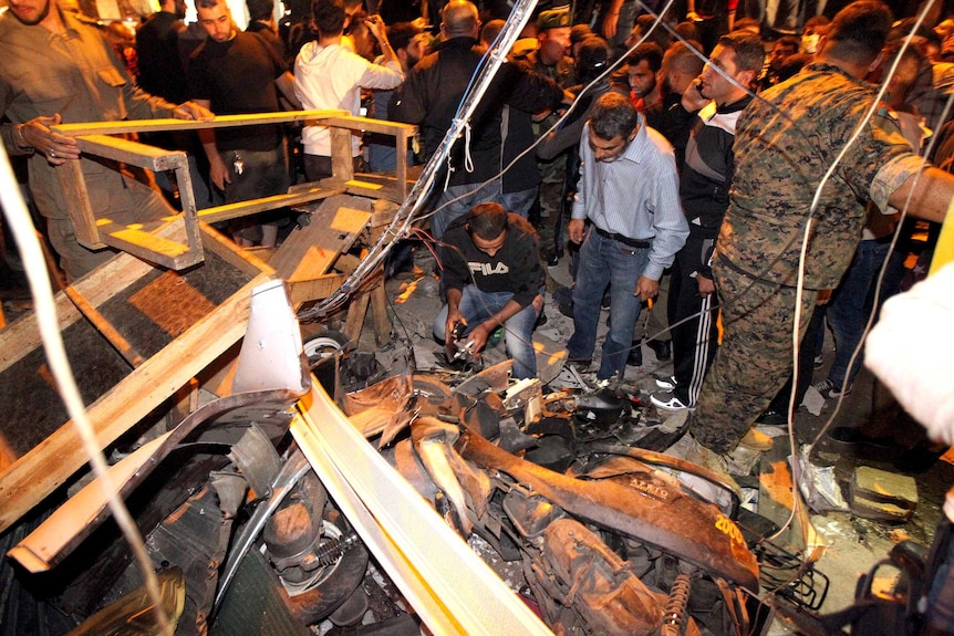 Night time photo of emergency personnel inspecting the debris at the site of a twin suicide bombing.