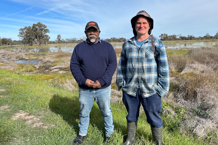 Ricky Kirby and Damien Cook standing in front of a shallow wetland which is a home for brolgas and other birds.