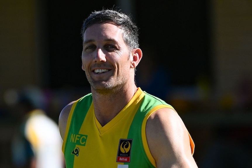 Man in football uniform smiles at the camera