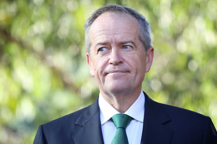 Head and shoulders shot of Bill Shorten in front of trees.