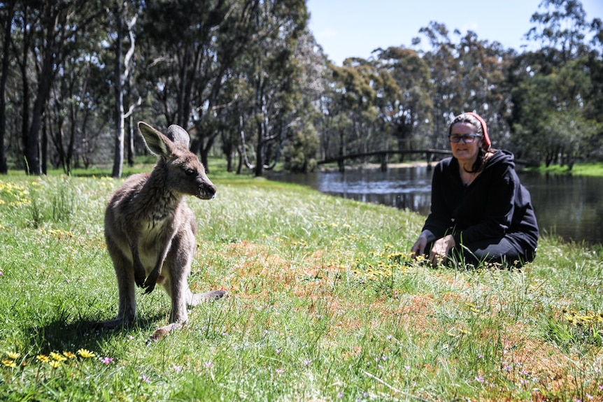 Vegan Nikki Medwell in the background with a rescued joey in the foreground.