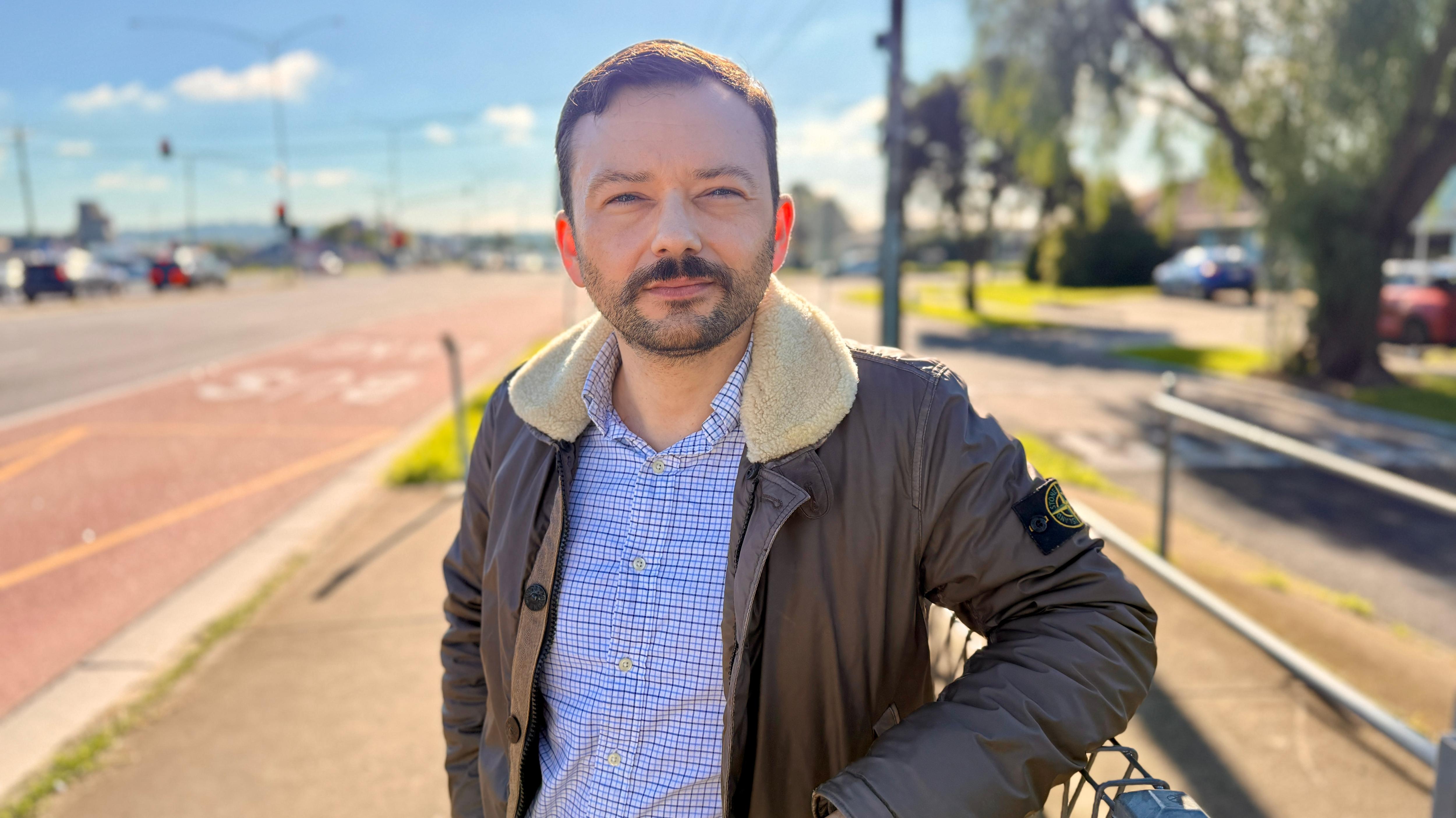 Man in leather jacket stands near highway