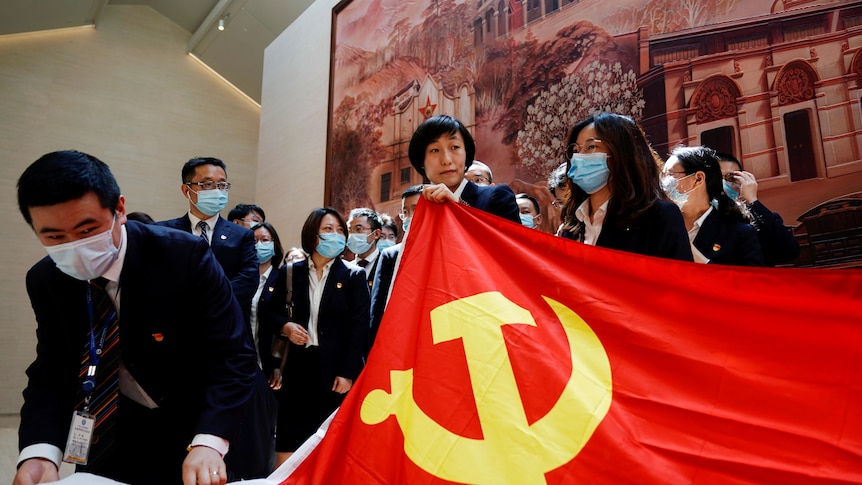 People hold a flag of the Communist Party of China