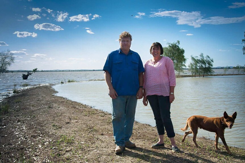 A man and woman standing on a patch of ground with flooding all around