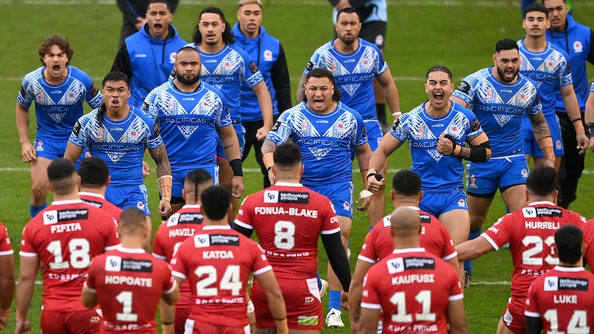 Samoan players are seen front-on performing their Siva Tau in front of Tongan players performing their Sipi Tau.