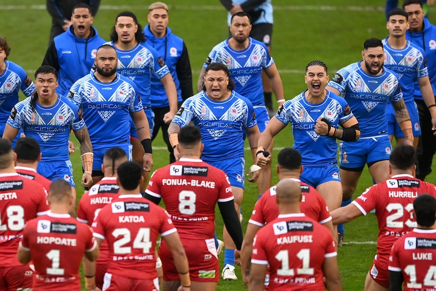 Samoan players are seen front-on performing their Siva Tau in front of Tongan players performing their Sipi Tau.