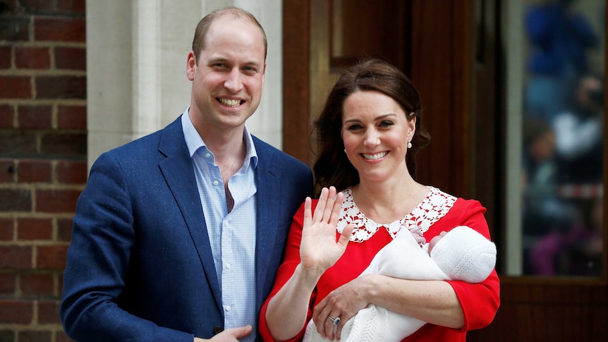 The Duchess of Cambridge holds waves while holding their new baby with Prince William next to her.