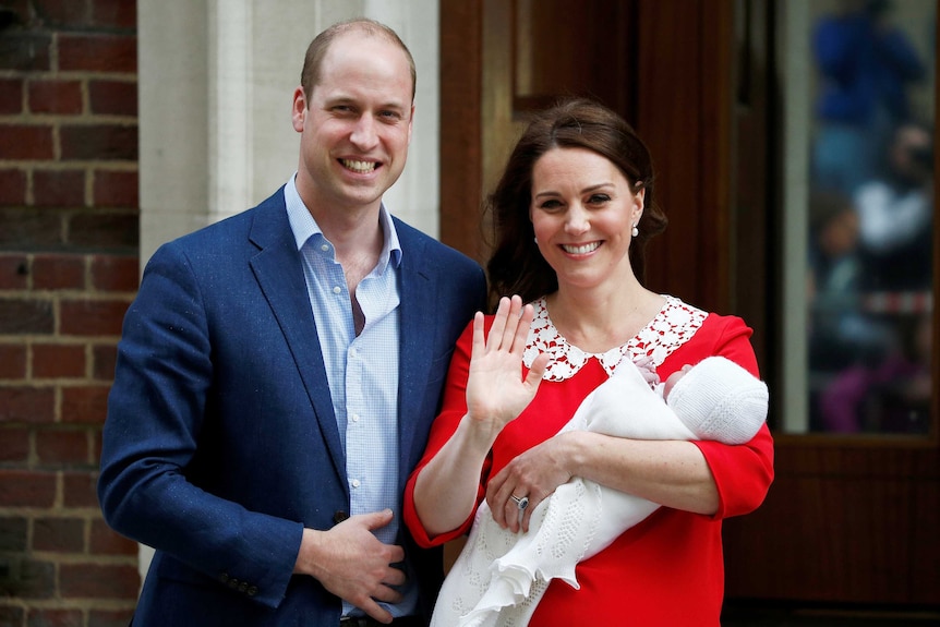 The Duchess of Cambridge holds the waves while holding their new baby with Prince William by her side.