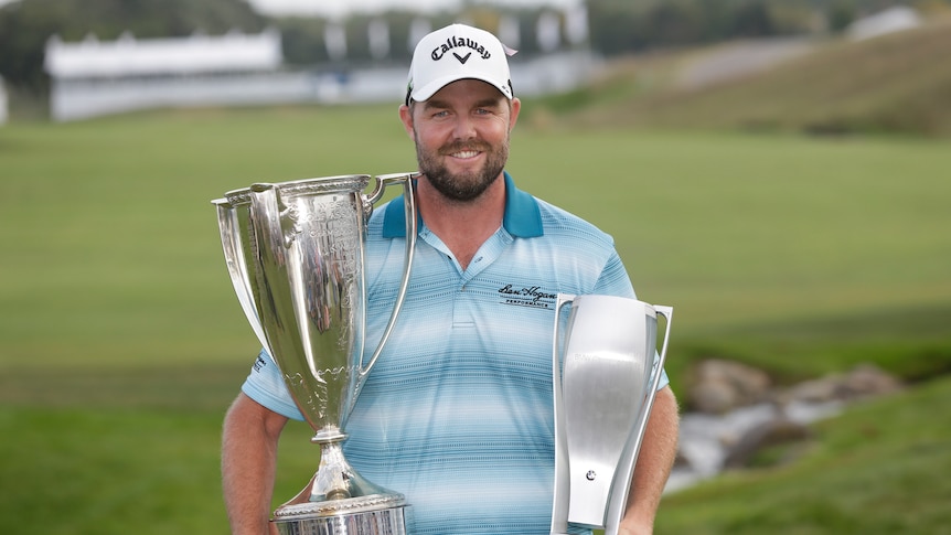 Marc Leishman smiles as he poses with the Wadley Cup, left, and the BMW Championship trophy.