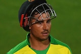 Marcus Stoinis walks with his helmet up on top of his head with a vacant look on his face