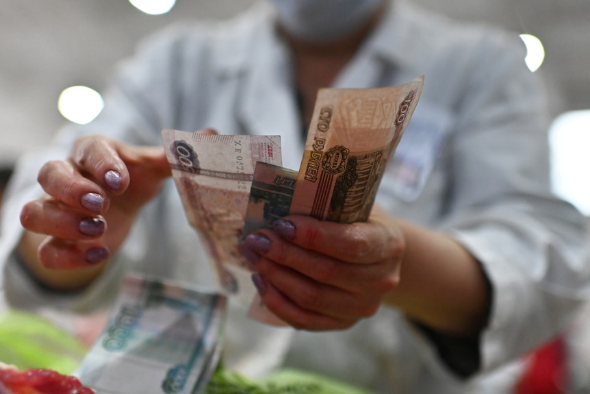 A vendor counts Russian rouble banknotes