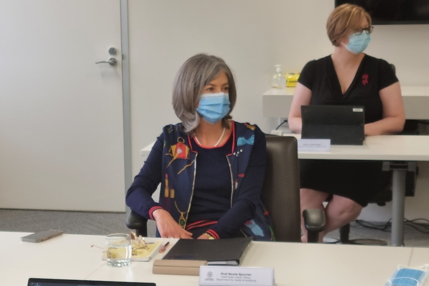 A woman wearing a colourful jacket sitting at a meeting table