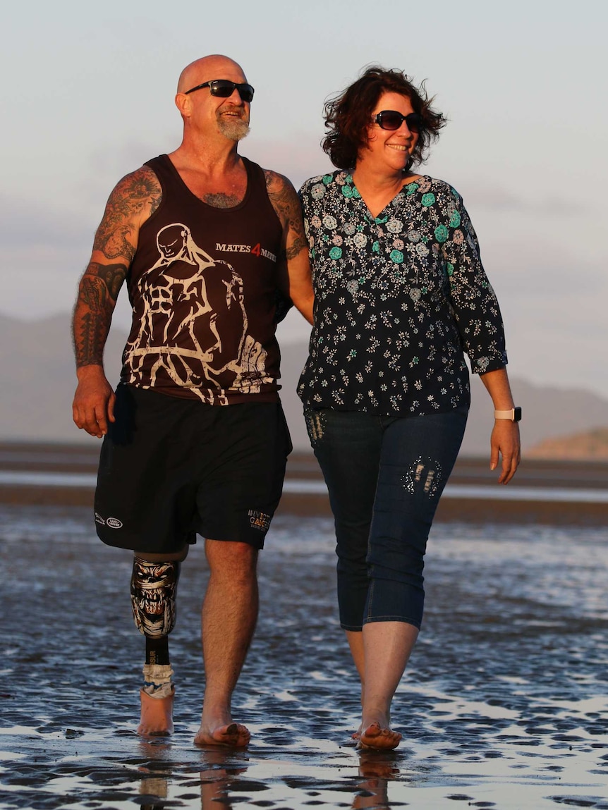 A couple walk on a beach.