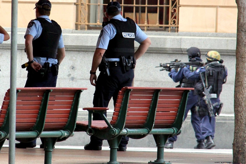 SERT officers with guns drawn make their way up the Queen Street Mall.