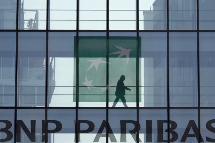A man is seen in silhouette as he walks behind the logo of BNP Paribas in a building in Issy-les-Moulineaux, near Paris, France.
