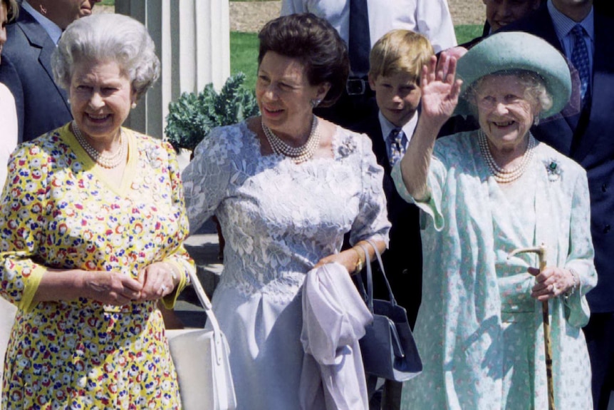 The Queen Mother waves, standing next to the Queen and Princess Margaret.