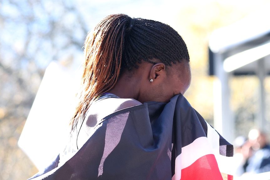 Viola Cheptoo covers her eyes with a Kenya flag