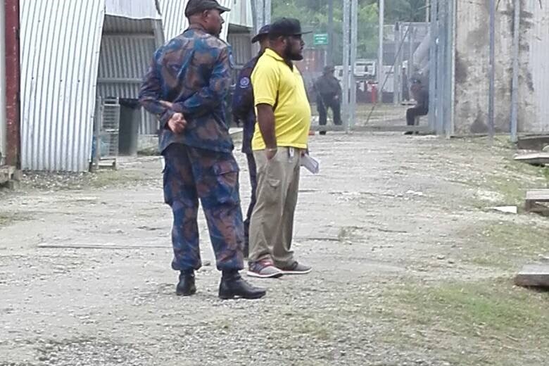Two uniformed men stand together inside the detention centre.