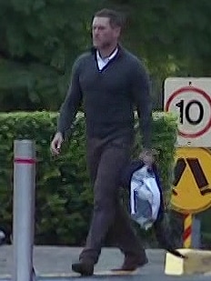 A stern man wearing dark trousers and a dark jumper carries a bag of possessions as he leaves the Silverwater prison.