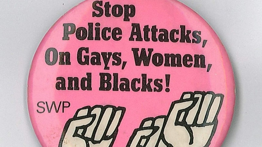 A pink coloured badge featuring illustration of three black raised fists.