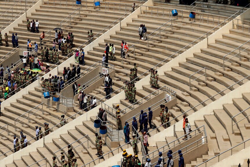 An aerial photo shows sparsely populated concrete stadium stands with patches of Zimbabweans standing.