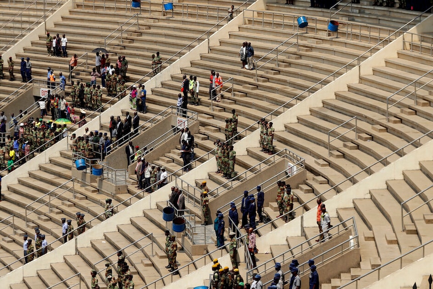 An aerial photo shows sparsely populated concrete stadium stands with patches of Zimbabweans standing.
