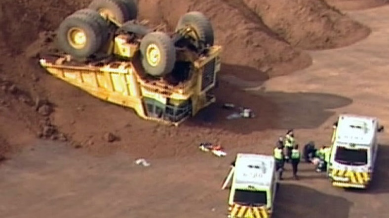 Aerial of flipped mining truck at quarry, ambulances
