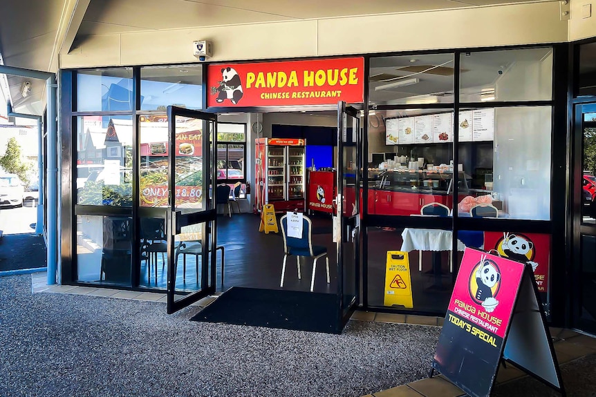 Shop front with red signs and yellow writing, and cartoon pandas