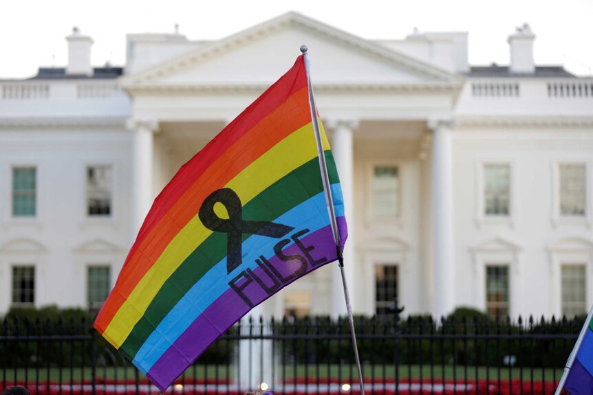 A rainbow flag is held up in front of the White House in the United States.