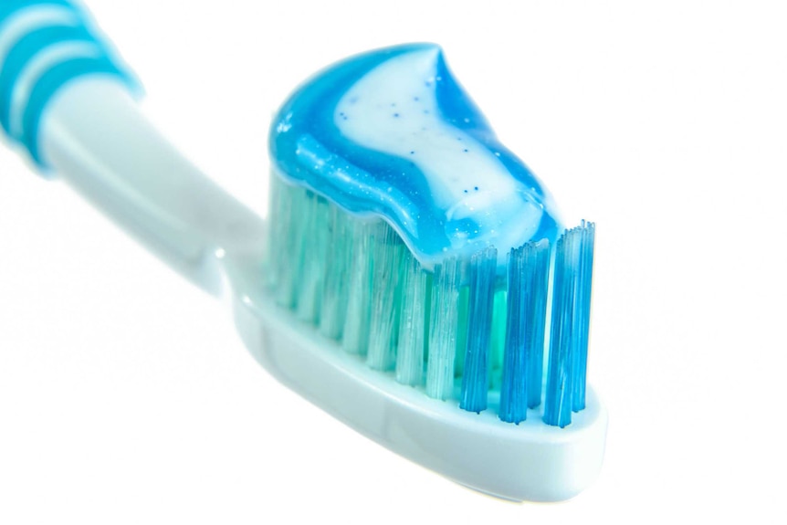 A smear of blue, sparkly toothpaste on a blue toothbrush.
