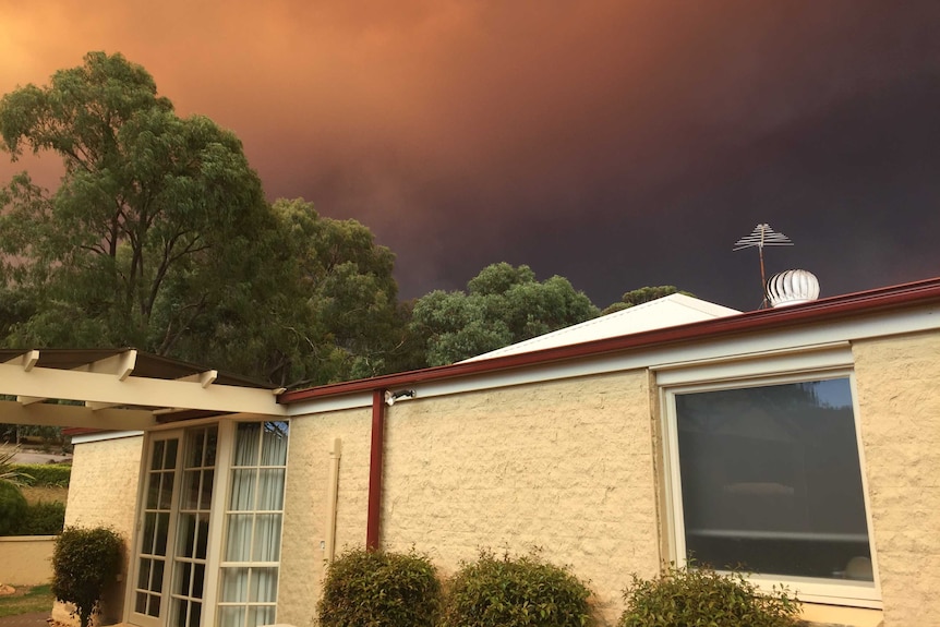 A sky covered in black smoke behind a house at Maryknoll, Victoria.