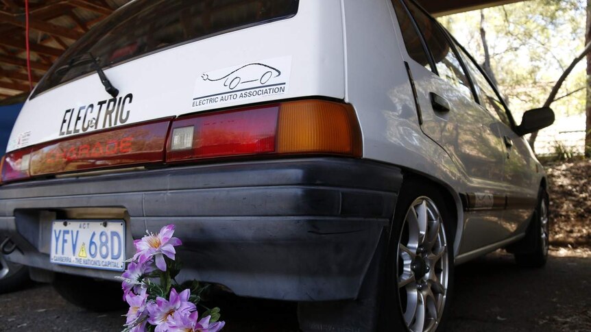 A small hatchback with flowers where the exhaust pipe should be.